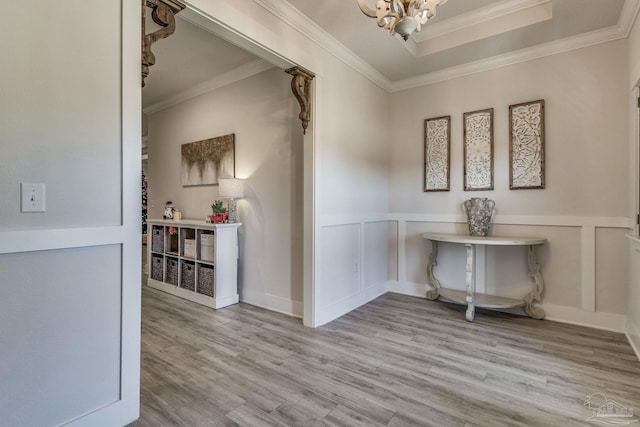 hallway featuring light hardwood / wood-style floors, an inviting chandelier, and crown molding