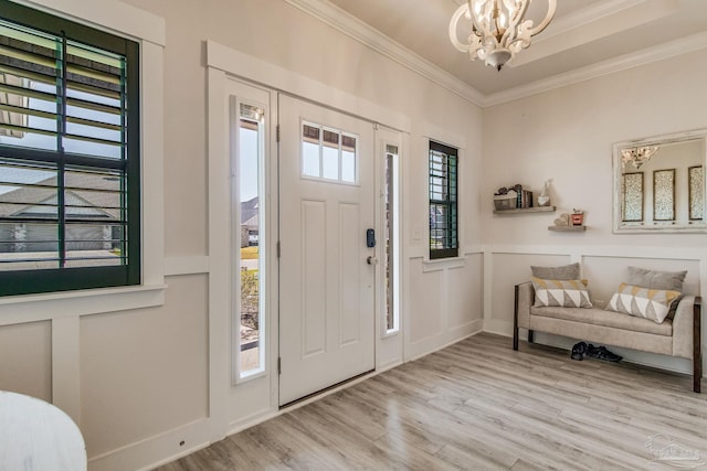 entryway featuring a notable chandelier, a healthy amount of sunlight, crown molding, and light hardwood / wood-style flooring