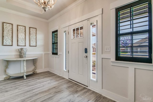 foyer entrance featuring light wood-type flooring, crown molding, and a healthy amount of sunlight