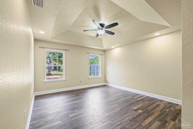 8114 Silver Maple Dr, Milton, FL 32583 - spare room with a textured wall, a tray ceiling, ceiling fan, dark wood-style flooring, and a textured ceiling