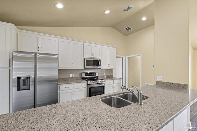 8114 Silver Maple Dr, Milton, FL 32583 - kitchen featuring appliances with stainless steel finishes, white cabinets, lofted ceiling, light stone countertops, and recessed lighting