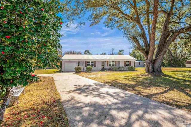 ranch-style house with an attached garage, metal roof, a front lawn, and concrete driveway