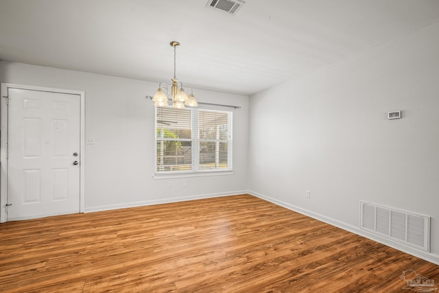 spare room with an inviting chandelier, visible vents, and light wood-style floors