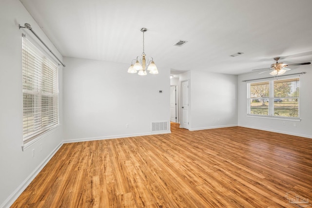 unfurnished room featuring ceiling fan with notable chandelier, light wood-style flooring, visible vents, and baseboards