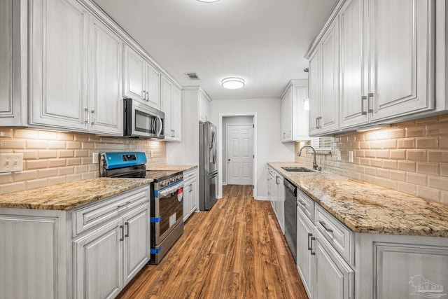 kitchen with visible vents, appliances with stainless steel finishes, wood finished floors, white cabinetry, and a sink