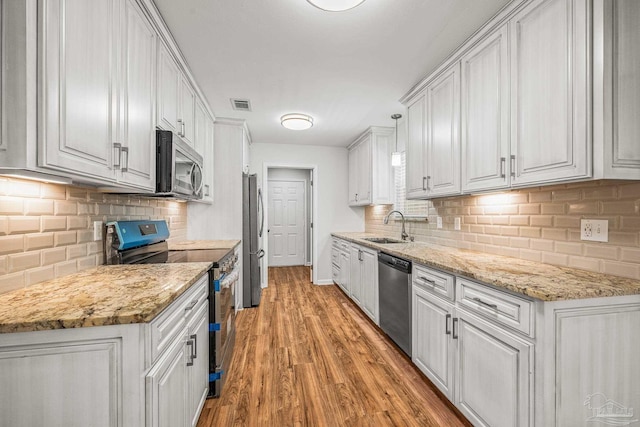 kitchen featuring stainless steel appliances, a sink, visible vents, light wood-style floors, and white cabinets