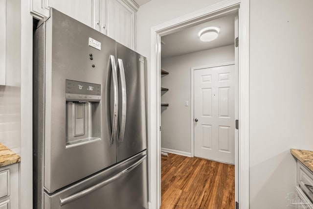 kitchen featuring white cabinets, stainless steel fridge, dark wood finished floors, and light stone countertops