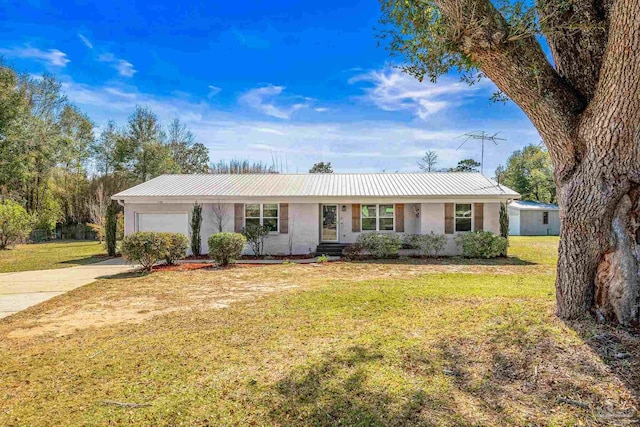 ranch-style home featuring a front lawn, metal roof, driveway, and an attached garage