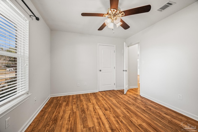 spare room featuring a ceiling fan, wood finished floors, visible vents, and baseboards