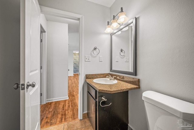 bathroom featuring toilet, baseboards, and vanity