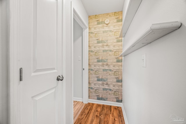 hallway with wood walls, baseboards, and wood finished floors