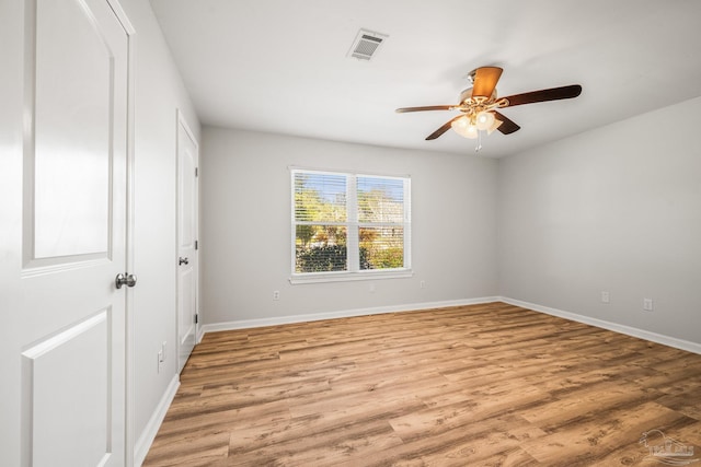 unfurnished room featuring light wood-style floors, visible vents, baseboards, and a ceiling fan