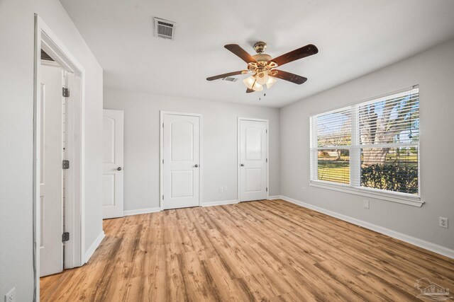 unfurnished bedroom with light wood-style floors, baseboards, visible vents, and ceiling fan