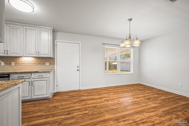 kitchen with a chandelier, tasteful backsplash, wood finished floors, and white cabinetry