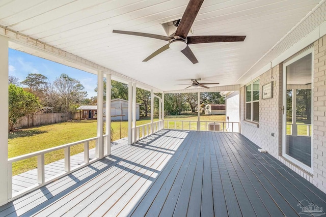 wooden terrace with a storage shed, ceiling fan, a fenced backyard, an outbuilding, and a yard