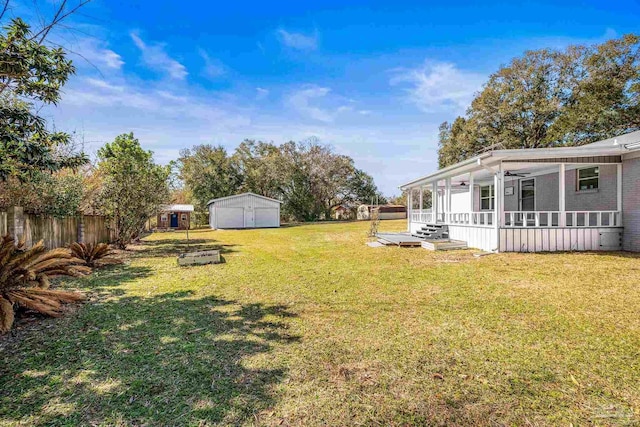 view of yard with a sunroom, fence, a storage unit, and an outdoor structure