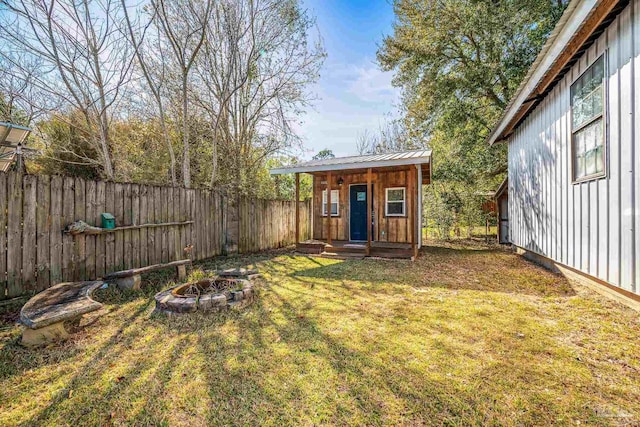 view of yard with a fire pit, an outdoor structure, and a fenced backyard