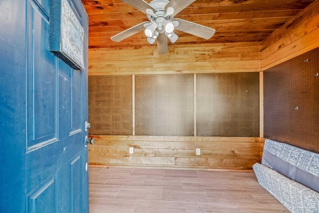 interior space featuring wooden ceiling, ceiling fan, and wooden walls