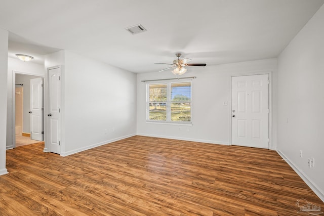 unfurnished room with a ceiling fan, baseboards, visible vents, and wood finished floors