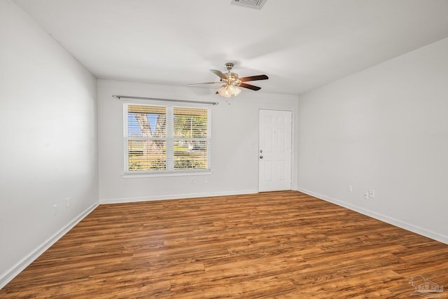 spare room with a ceiling fan, visible vents, baseboards, and wood finished floors