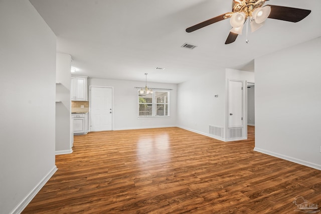 unfurnished living room featuring baseboards, visible vents, and wood finished floors