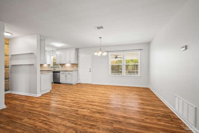 kitchen with visible vents, decorative backsplash, dishwasher, wood finished floors, and an inviting chandelier