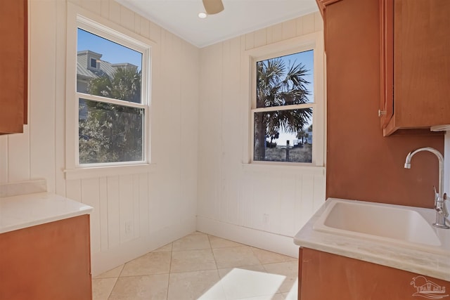 interior space featuring light tile patterned flooring, a sink, a ceiling fan, light countertops, and brown cabinets