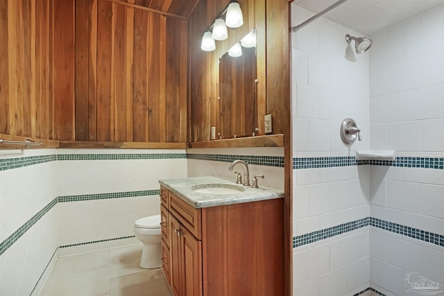 bathroom featuring toilet, tiled shower, vanity, and tile patterned floors