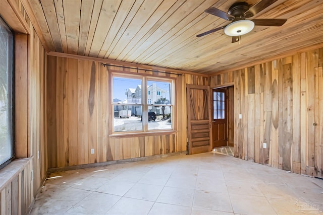 spare room featuring wooden ceiling, ceiling fan, wood walls, and light tile patterned floors