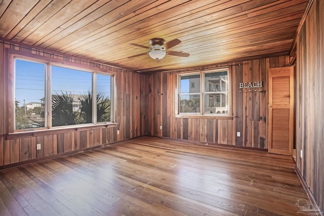 empty room with wooden ceiling, a wealth of natural light, and wood finished floors