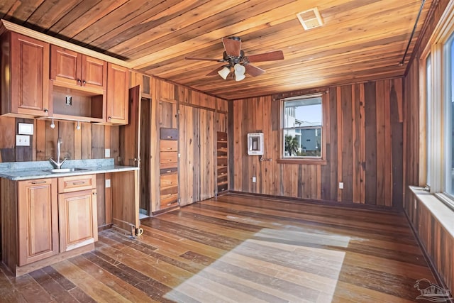 kitchen with dark wood-style floors, wood ceiling, brown cabinets, light countertops, and wood walls