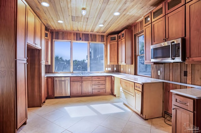 kitchen with wood ceiling, glass insert cabinets, appliances with stainless steel finishes, light countertops, and a sink