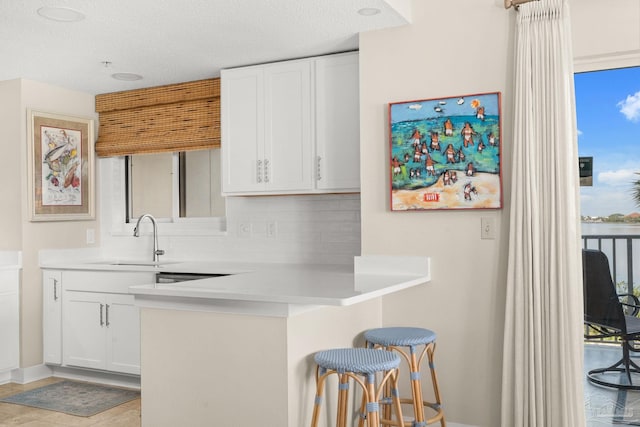 751 Pensacola Beach Blvd Unit 2F, Pensacola Beach, FL 32561 - kitchen with a breakfast bar, white cabinetry, backsplash, light countertops, and a textured ceiling