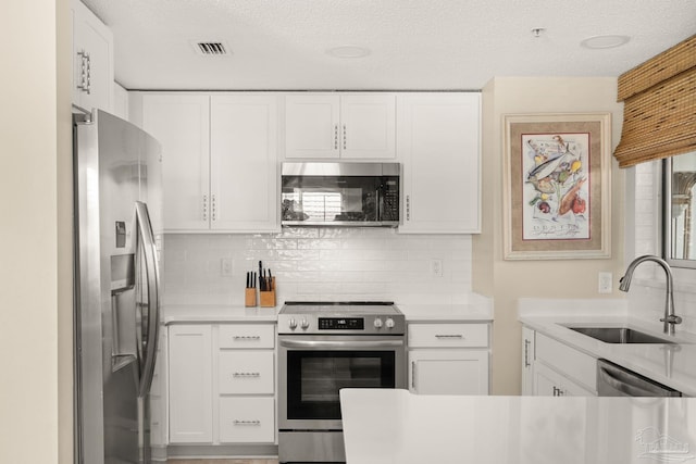 751 Pensacola Beach Blvd Unit 2F, Pensacola Beach, FL 32561 - kitchen featuring stainless steel appliances, light countertops, backsplash, white cabinets, and a textured ceiling