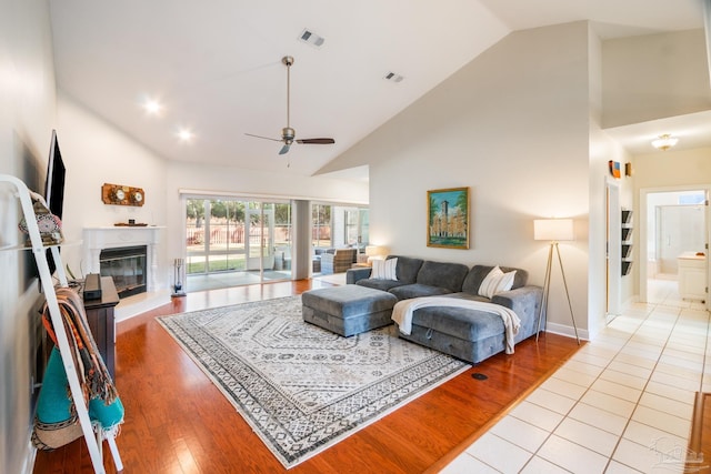 living room with ceiling fan, high vaulted ceiling, and light hardwood / wood-style flooring