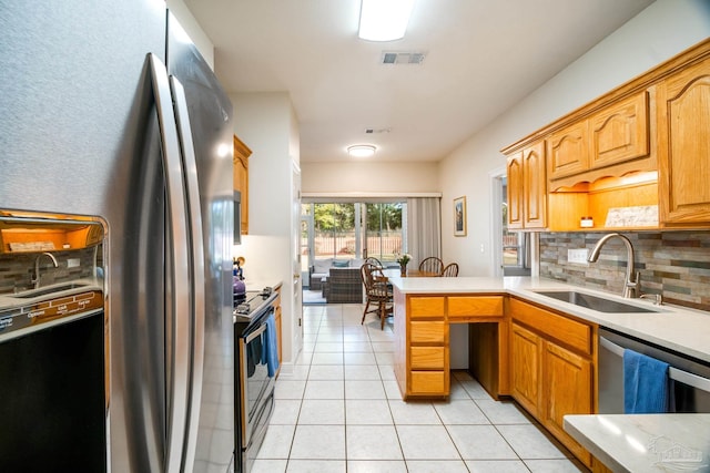 kitchen featuring sink, light tile patterned floors, appliances with stainless steel finishes, decorative backsplash, and kitchen peninsula