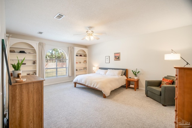 carpeted bedroom featuring ceiling fan and a textured ceiling