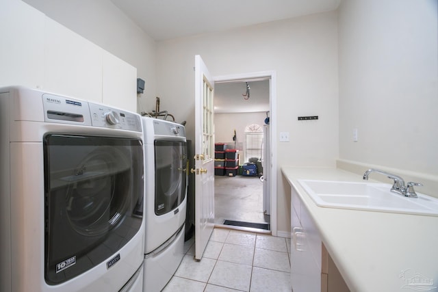 clothes washing area with sink, light tile patterned floors, cabinets, and independent washer and dryer