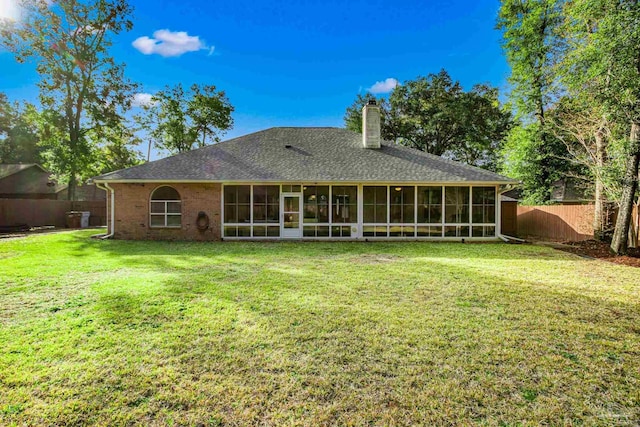 rear view of property featuring a sunroom and a yard