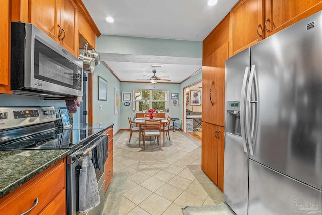 kitchen with light tile patterned floors, crown molding, ceiling fan, appliances with stainless steel finishes, and dark stone counters