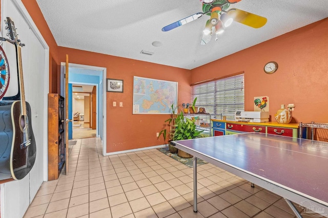 game room featuring light tile patterned flooring, ceiling fan, and a textured ceiling