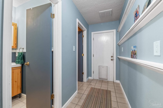 corridor featuring light tile patterned floors and a textured ceiling