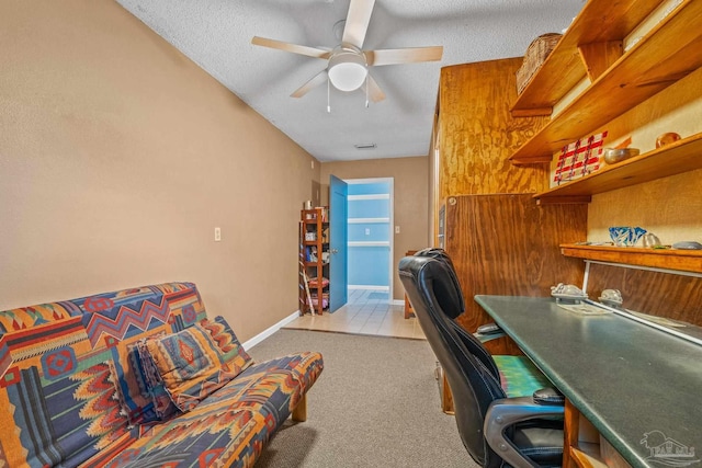 carpeted home office with a textured ceiling and ceiling fan