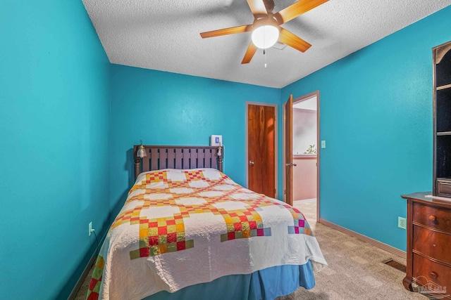 bedroom featuring ceiling fan, light colored carpet, and a textured ceiling