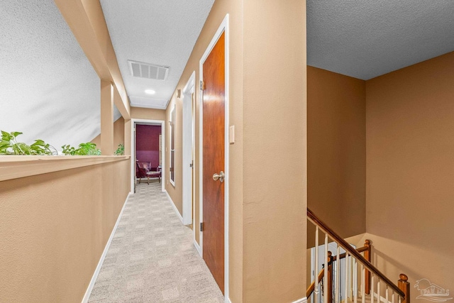 hall with lofted ceiling, light carpet, and a textured ceiling