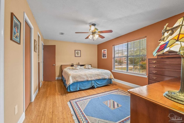 bedroom featuring ceiling fan, light hardwood / wood-style floors, and a textured ceiling