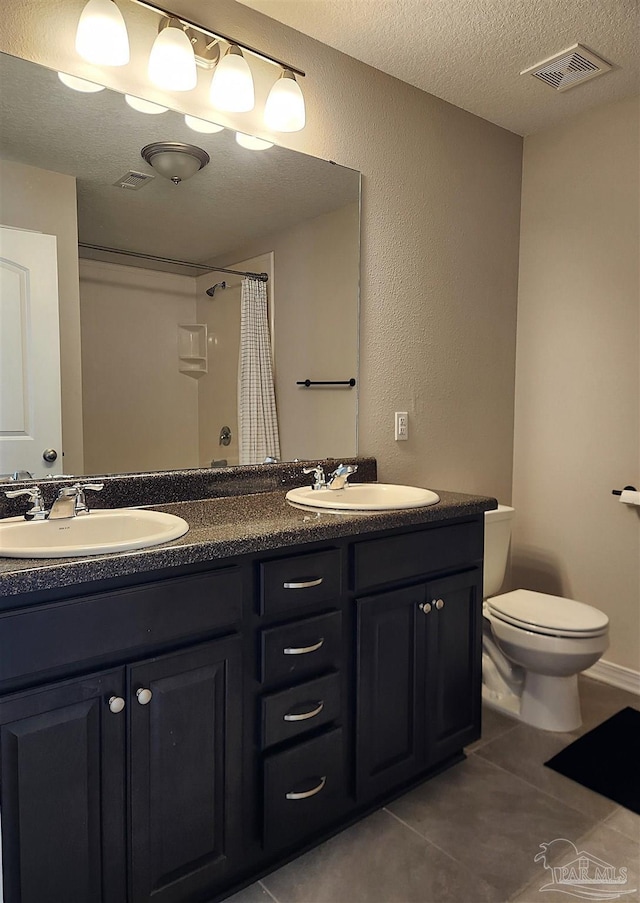 bathroom with curtained shower, tile patterned floors, a textured ceiling, toilet, and vanity