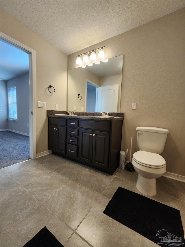 bathroom with tile patterned flooring, vanity, toilet, and a textured ceiling