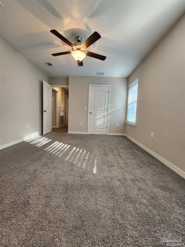 unfurnished bedroom featuring ceiling fan, dark carpet, a textured ceiling, and a closet