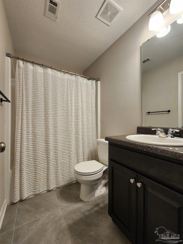 bathroom featuring vanity, tile patterned floors, a textured ceiling, and toilet